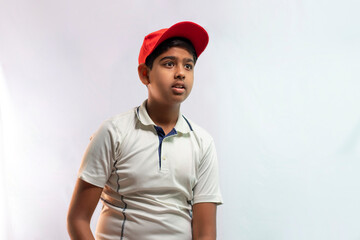 A boy in cricket uniform with cap