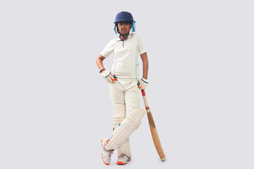 full length of a boy in cricket uniform  standing with bat 
