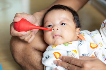 Dad hand use baby nasal aspirator mucus nose suction sucking the saliva from baby's nose cleaning