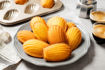 Perfect French madeleine cookies, buttery and delicate, served with cup of coffee. Light gray background. - obrazy, fototapety, plakaty