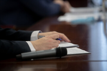 Hands of an official, speaker or boss during a press conference - meeting with the press. Speaker at the talks. Blank plate to indicate the name and position. Close-up. No face