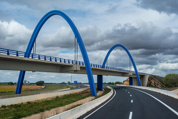 Highway making a curve and passing under a bridge with a sky of beautiful clouds.