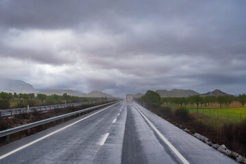 Fototapeta premium Truck circulating on a rainy day, raising a cloud of water as it passed.