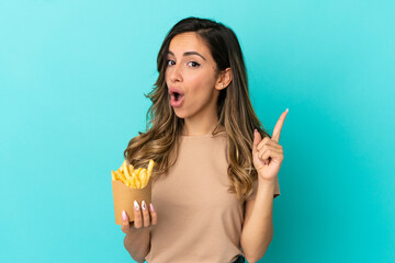 Young woman holding fried chips over isolated background intending to realizes the solution while lifting a finger up