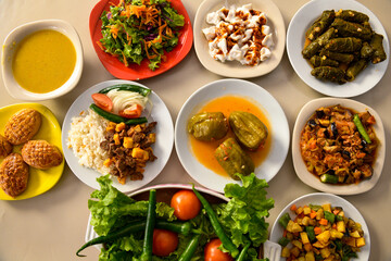 Top view of table scene with assorted take out or delivery foods. Meat and chicken doner kebab sandwich, wrap and on the plate with vegetables and sauce, including fries and pickles.