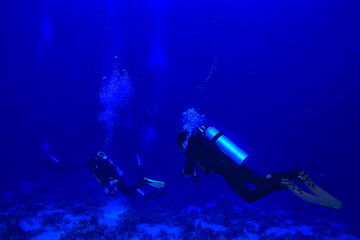 Obraz na płótnie Canvas divers underwater at depth in the blue sea background