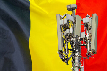 Telecommunications tower with a 5G cellular network antenna agains flag of Belgium....