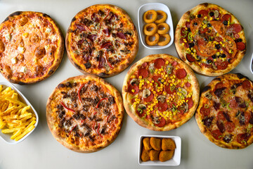 Top view of table scene with assorted take out or delivery foods. Meat and chicken doner kebab sandwich, wrap and on the plate with vegetables and sauce, including fries and pickles.