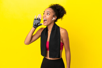 Young African sport woman isolated on yellow background shouting with mouth wide open to the lateral