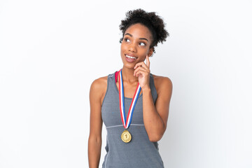 Fototapeta na wymiar Young African American woman with medals isolated on white background thinking an idea while looking up