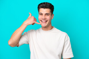 Fototapeta premium Young handsome caucasian man isolated on blue bakcground making phone gesture. Call me back sign