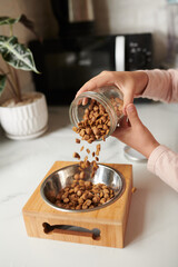 Close-up image of girl filling bowl of her dog with kibble