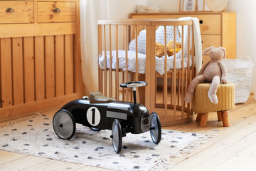 Retro style child Black racing car in a children room. Modern interior of child bedroom. Hygge. Kindergarten. Cozy Scandinavian baby room: crib with bedding and toys. Light Room with Wooden Cot Cradle © stock_studio