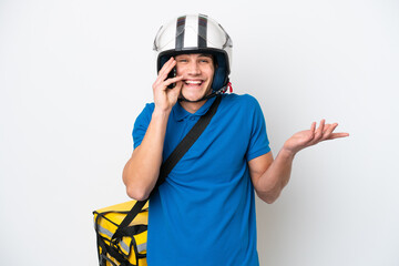 Young caucasian man with thermal backpack isolated on white background keeping a conversation with the mobile phone with someone