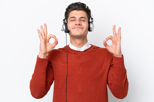 Telemarketer caucasian man working with a headset isolated on white background in zen pose