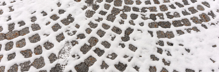 Old cobblestone pavement with snow in winter. Panoramic image