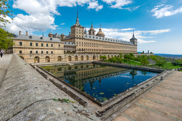 monastery of San Lorenzo de El Escorial with tourists strolling through its gardens and patios in Madrid