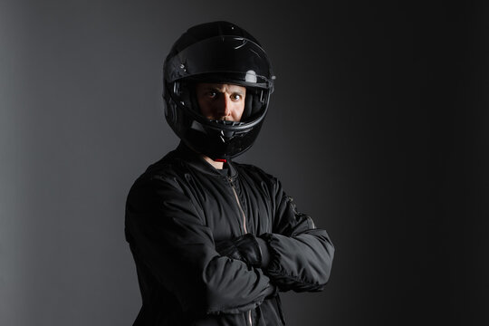 Studio shot of Motorcyclist biker in black equipment with crossed arms.