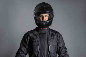 Studio shot of Motorcyclist biker in black equipment looking at camera.
