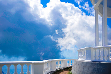 a combination of white and blue in a panorama of clouds flying across the blue sky on top of a mountain with white columns with empty space for text