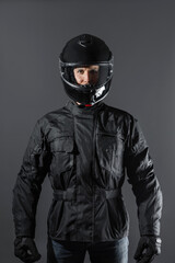 Studio shot of Motorcyclist biker in black equipment looking at camera.