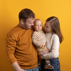 mom, dad and boy on a yellow background. A family with a baby in their arms.