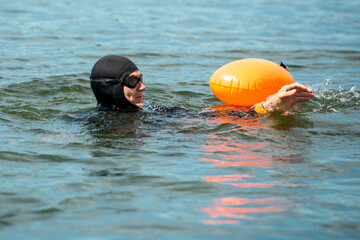 athlete swimmer in a wetsuit with a buoy, in the water