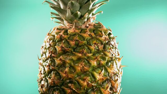 Half Pineapple falling and splashing on turquoise background. Food levitation concept. Slow Motion