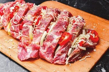 Obraz premium Loin meat with spices, cut into pieces, lies on a cutting board for further cooking on a fire or in the oven.