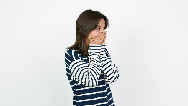 Young brunette woman covering mouth with hands. Can not speak over isolated background