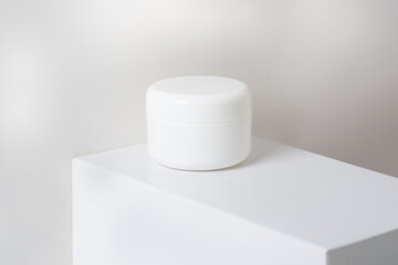 white box of body cream on a pedestal on a light background