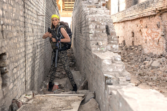 Young woman with gun in ruined old structure hide and look