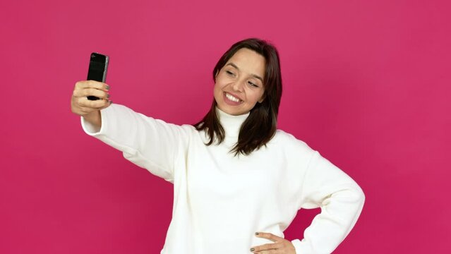Young brunette woman using mobile phone and doing a selfie over isolated background