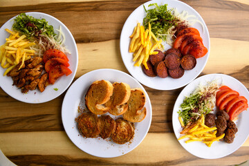 Top view of table scene with assorted take out or delivery foods. Meat and chicken doner kebab sandwich, wrap and on the plate with vegetables and sauce, including fries and pickles.