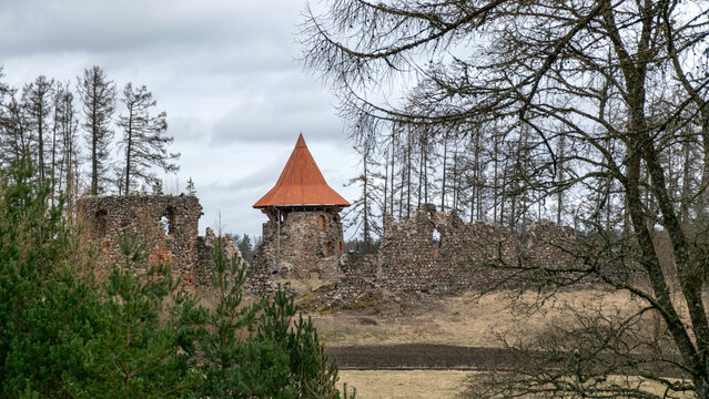 spring landscape with a view of the castle ruins, the new bright orange roof of the castle tower stands out, Ergeme castle ruins, Valka district, Latvia