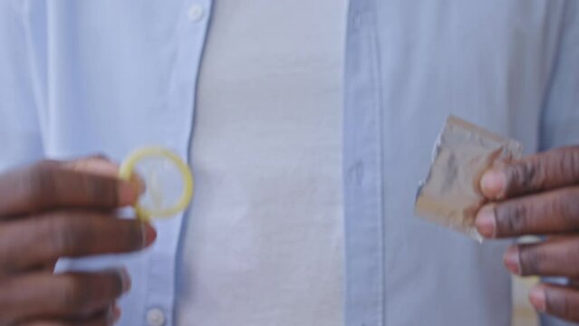 Close-up of male hands taking out condom from package, std prevention, safe sex