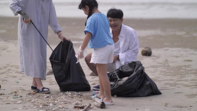 Grandfather And Grandmother And Granddaughter Are Picking Up Trash On The Beach While On Vacation.