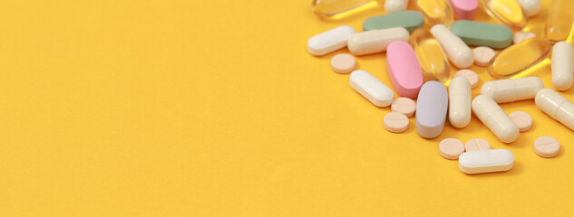 Pill bottle spilling out. colorful pills on to surface tablets on a table yellow background. top view. drug medical healthcare concept