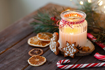 Christmas composition with gingerbread cookies, candy cane and a candle. Cozy home atmosphere, delicious sweet holiday dessert. Traditional spices: cinnamon, anise, cardamom