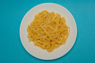 Spaghetti pasta on a white plate on a blue background.