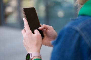 Woman holding smartphone on street walk closeup