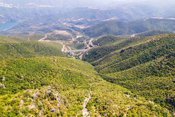 Naklejka na ściany i meble Panoramic view of top of mountains, highway bridge in sunny summer weather in Greece. Aerial view