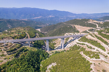 Panoramic view of top of mountains, highway bridge in sunny summer weather in Greece. Aerial view
