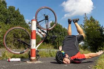 Fotobehang The unhappy cyclist falls of the bike beside the barrier on a bicycle path. © milkovasa