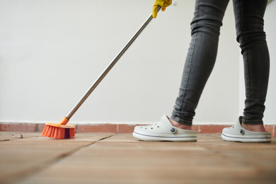 Cropped image of cleaner sweeping tile floor in backyard