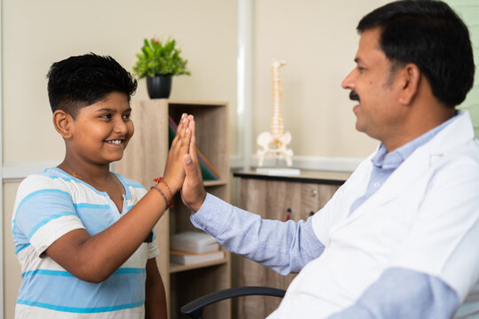 Friendly Doctor Playing With Sick Child At Hospital To Make Kid Comfort - Concept Of Pediatrician, Happiness And Medical Treatment.