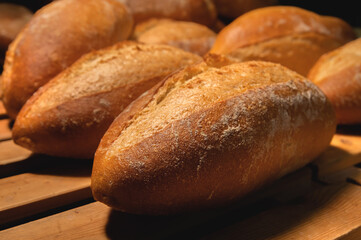 Fresh crispy hot delicious craft artisan bread. Many loaves lie on a wooden pallet