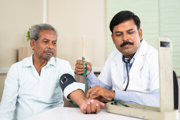 doctor checking blood pressure of elderly patient at hospital - concept of routine health checkup,...