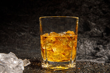 glass of whiskey with ice on asphalt