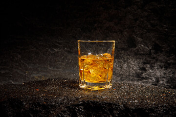 glass of whiskey with ice on asphalt